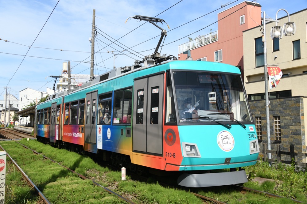 若林踏切の停止信号で停車中の310編成「SDGsトレイン美しい時代へ号」／2023年4月29日 若林〜西太子堂間